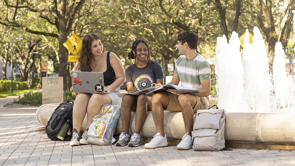 Students sitting by a fountain on campus